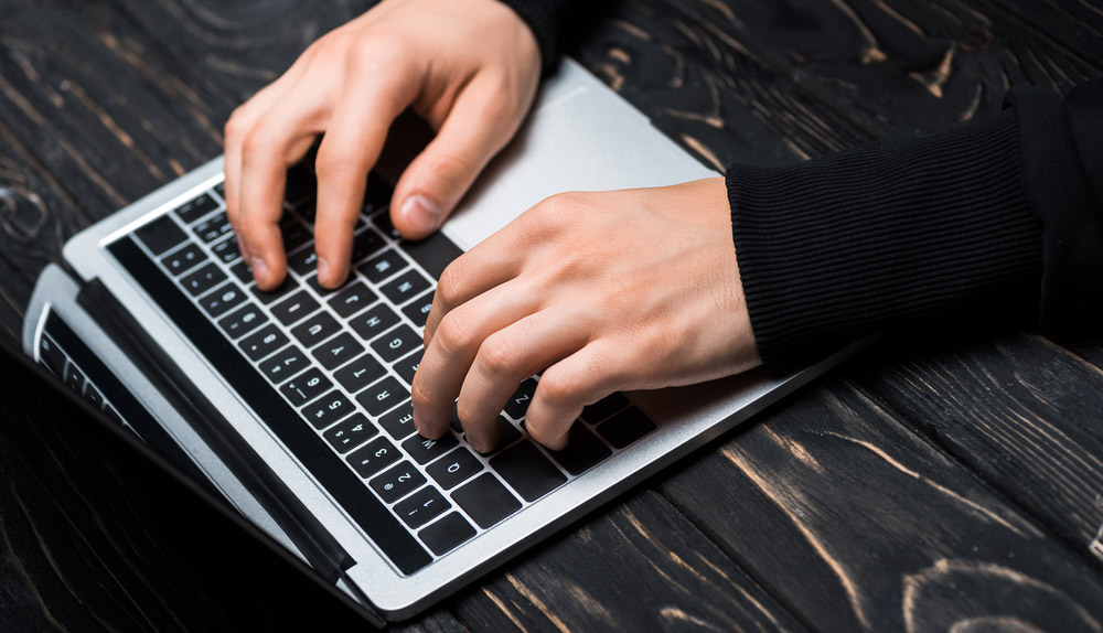 Các tay đang gõ trên bàn phím laptop.